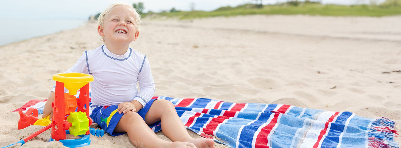 boy in rashguard and swim trunks playing at beach