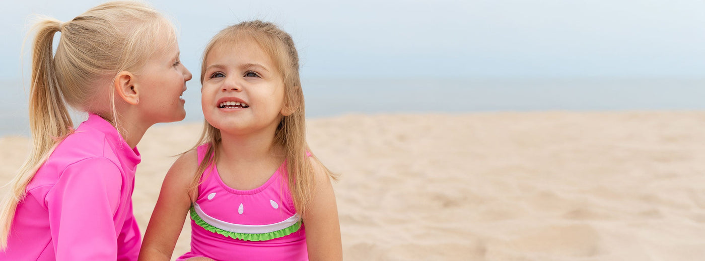 two girls in bright pink suits at beach