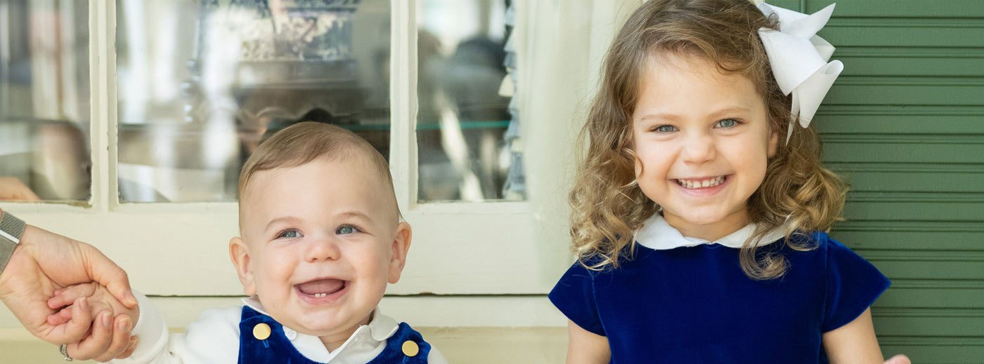 two young children smiling in blue velvet outfits