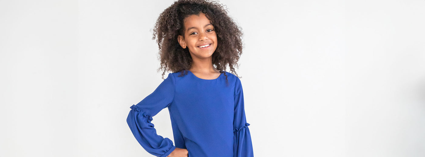 young girl posing in a studio in a blue dress