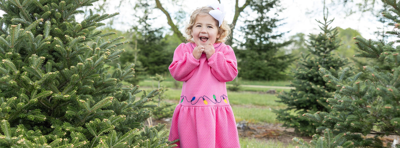 young girl in pink holiday dress at a tree farm