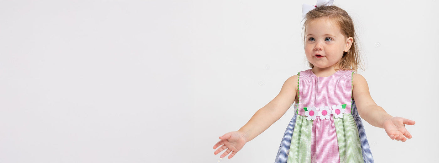 girl in stripe dress with flowers holding arms out