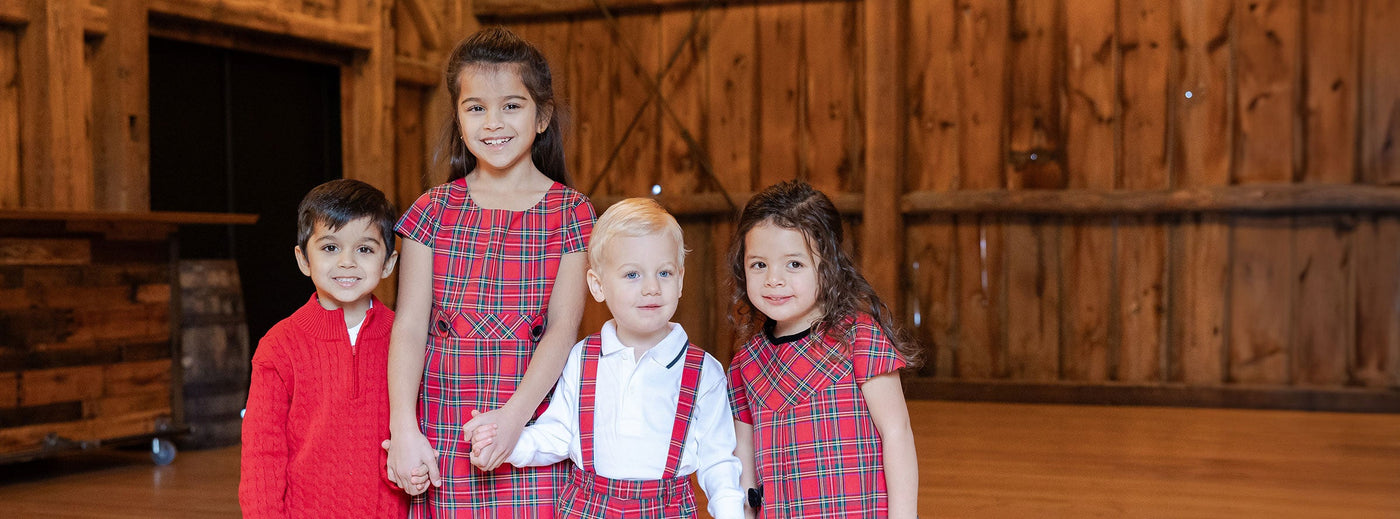 two girls and two boys in matching red tartan holiday outfits