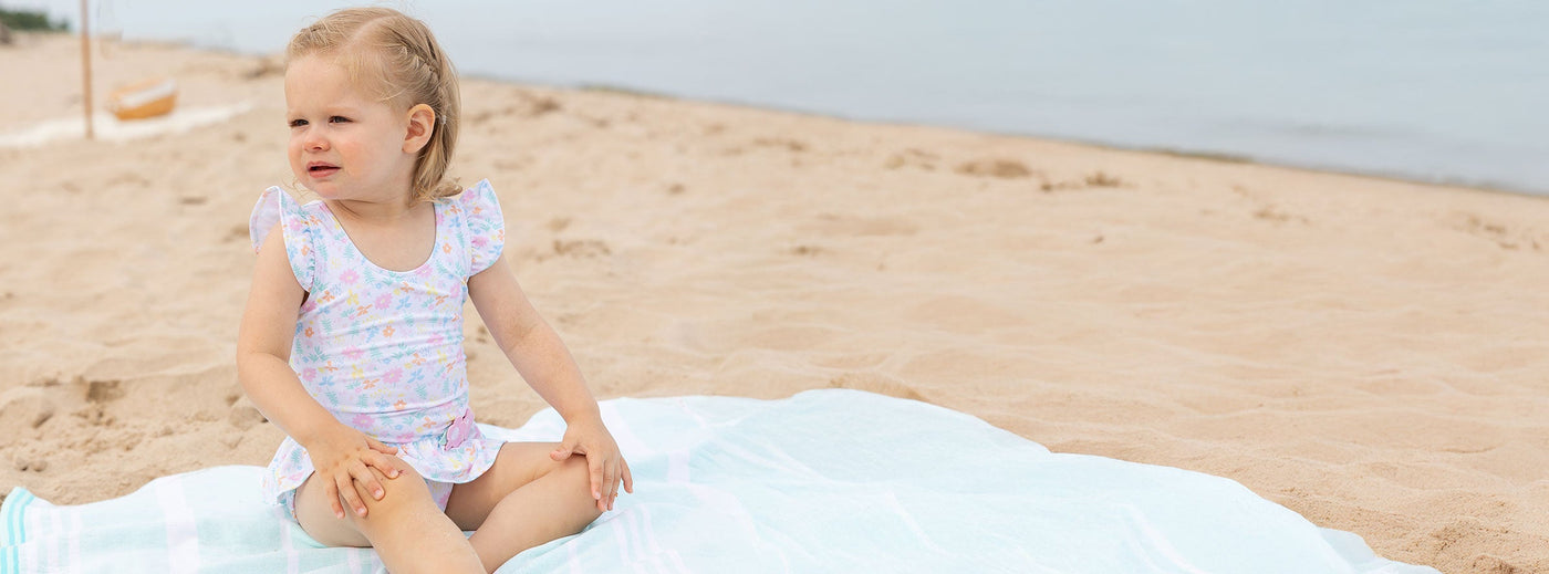 young girl on blanket at beach in swimsuit