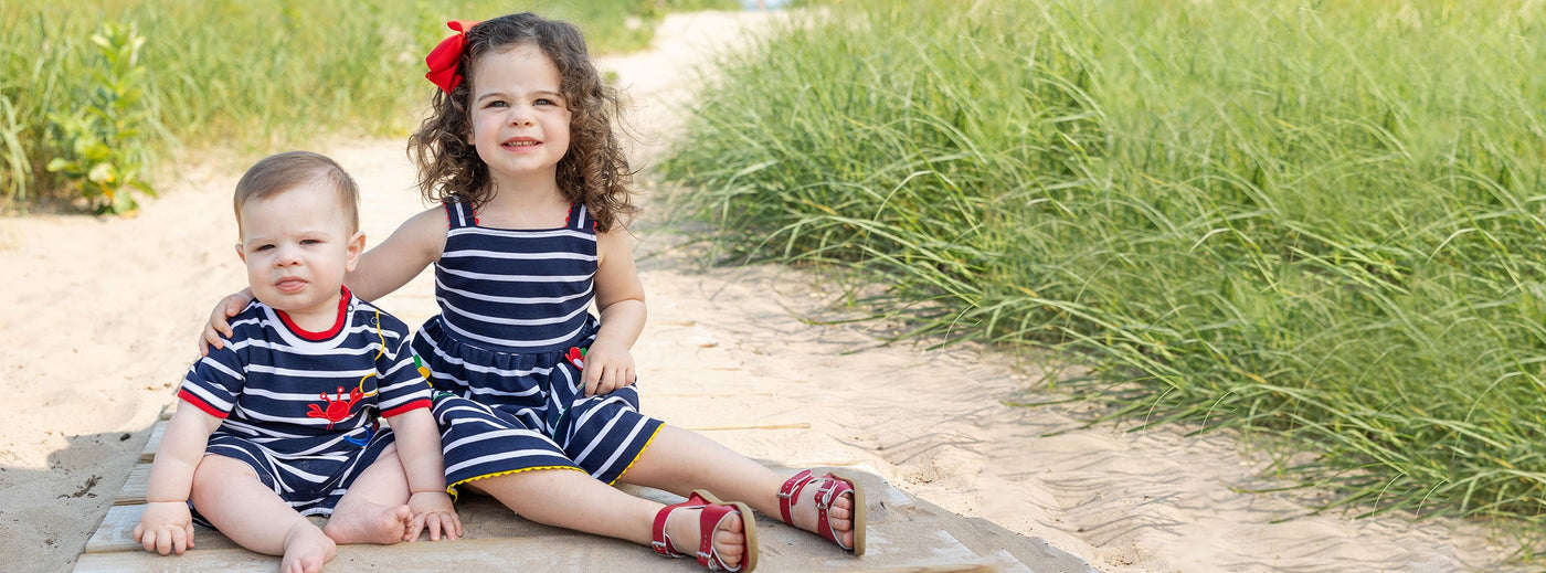 baby and young girl in the sand