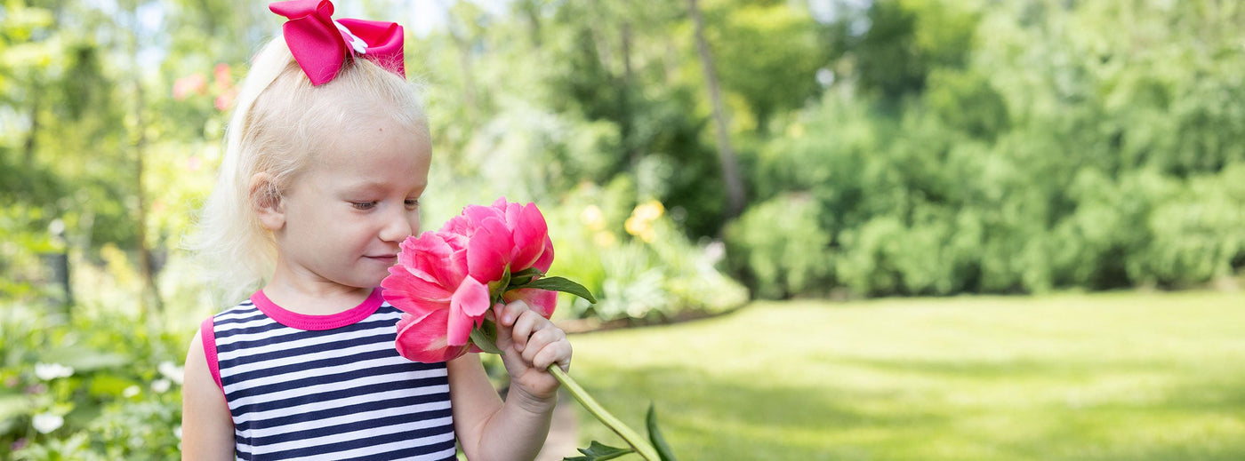 girl smelling peony flower in a garden