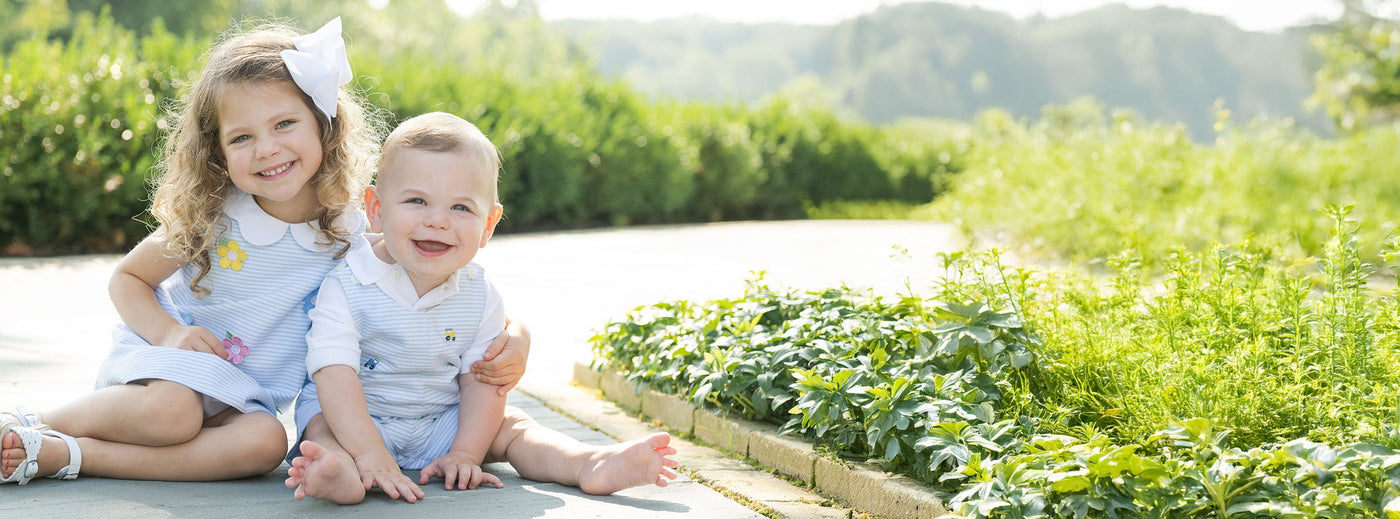 young girl and toddler boy sitting on pathway