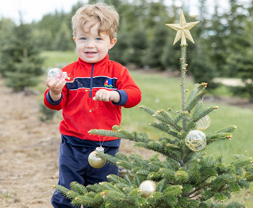 toddler boy by christmas tree in red sweater