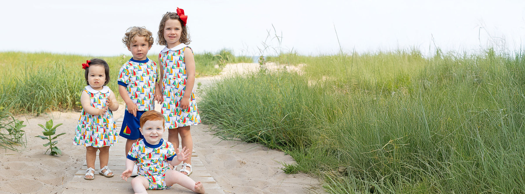 four children in matching sailboat outfits