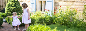 two girls in pink stripe dresses in a garden