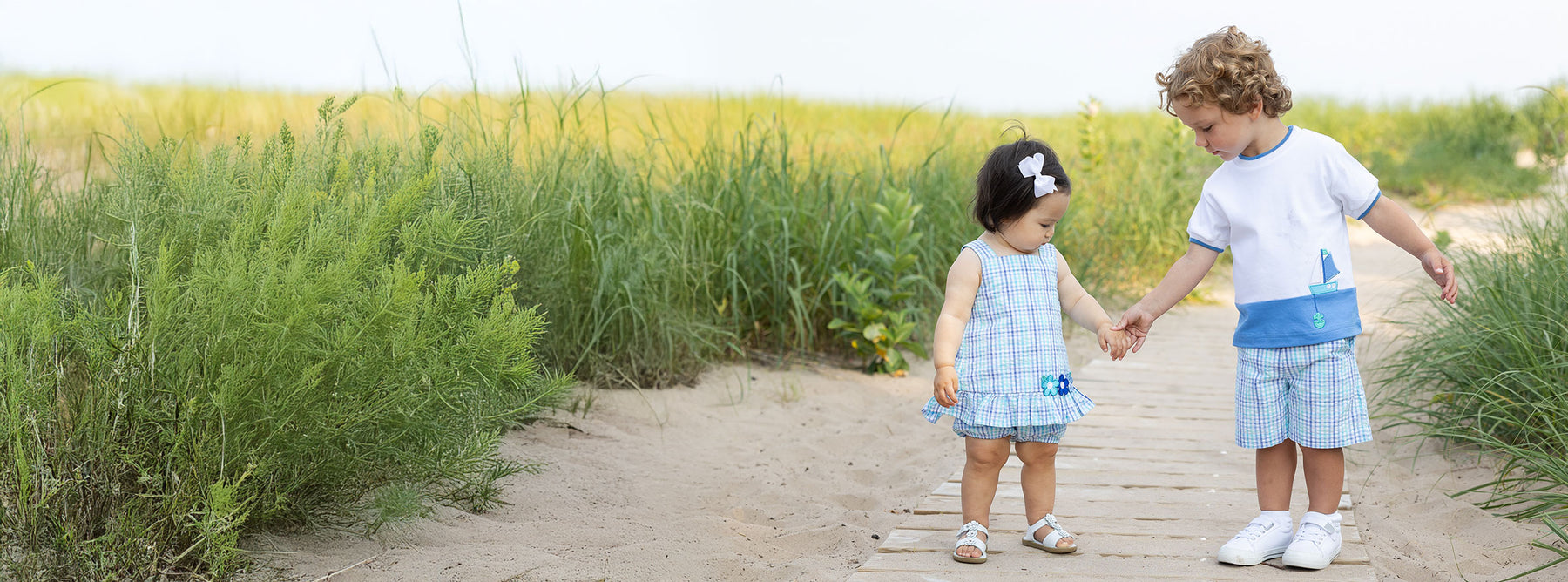 two children on boardwalk in matching blue plaid outfits